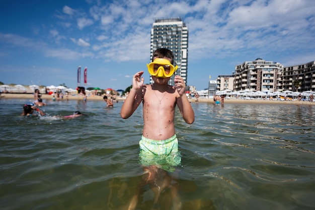 Kleiner Junge schwimmt mit gelber Schnorchelmaske im Meer