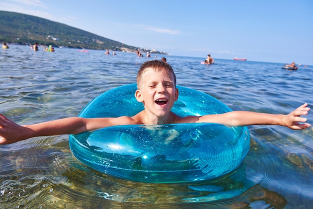 Kleiner Junge schwimmt mit Spielzeug-Rettungsringen