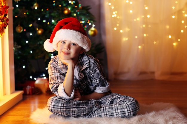 Kleiner Junge sitzt am Kamin im Zimmer fireplace