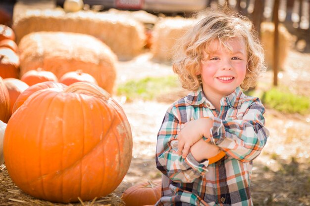 Kleiner Junge sitzt und hält seinen Kürbis bei Pumpkin PatchxA