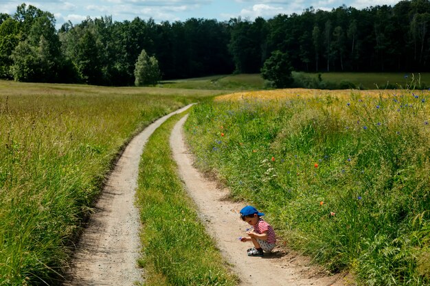 Kleiner Junge spielt auf Landstraße