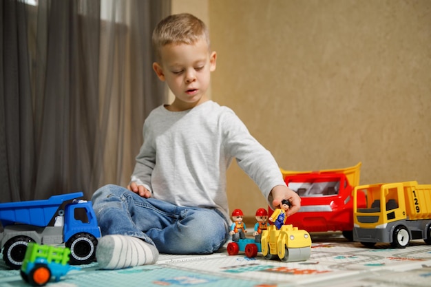 Foto kleiner junge spielt mit auto- und lkw-spielzeug