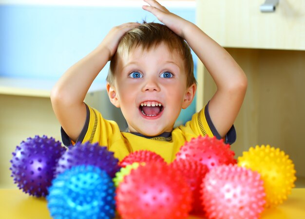 Kleiner Junge spielt mit bunten Bällen