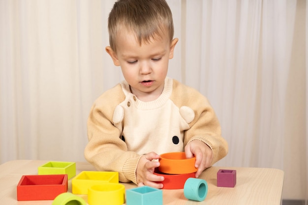 Foto kleiner junge spielt mit bunten holz-montessori-spielzeug