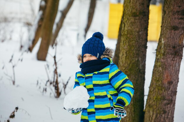 Kleiner Junge spielt mit Schnee und macht Schneebälle