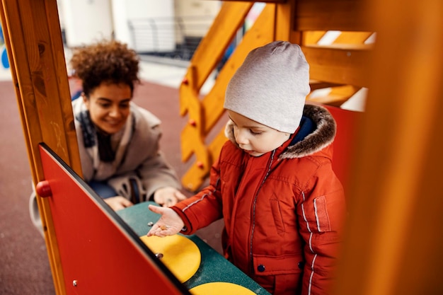 Kleiner Junge spielt mit seinem Babysitter auf dem Spielplatz