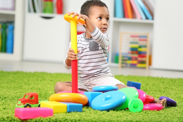 Kleiner Junge spielt mit seinen Spielsachen im Zimmer