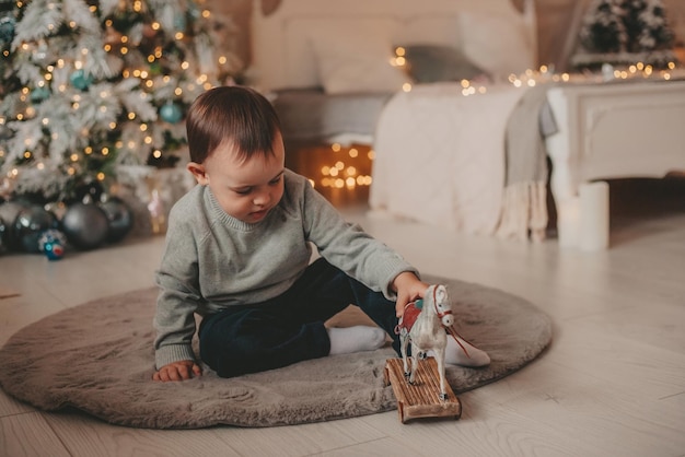 kleiner Junge spielt mit Spielzeug in Weihnachtsschmuck