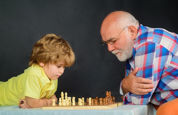 Kleiner Junge spielt Schach mit Großvater Opa und Enkel spielen Schach und genießen die Freizeit