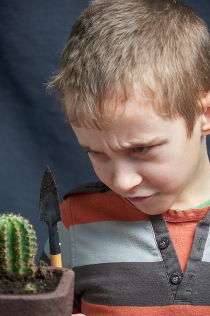 Foto kleiner junge stellte seinen zimmerpflanzenkaktus ab