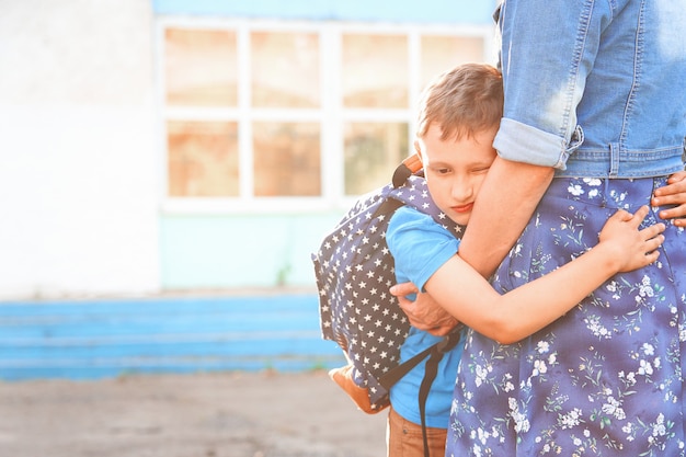 Kleiner Junge umarmt seine Mutter, bevor er zur Schule geht