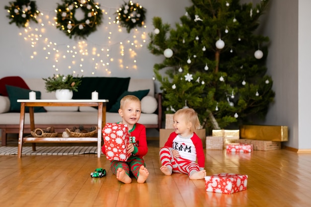 Kleiner Junge und ein Mädchen in gemütlichen Pyjamas und Weihnachtsmannmützen