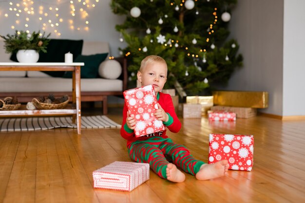 Kleiner Junge und ein Mädchen in gemütlichen Pyjamas und Weihnachtsmannmützen