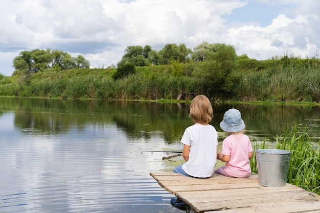 Kleiner Junge und Mädchen, die in einem Teich fischen