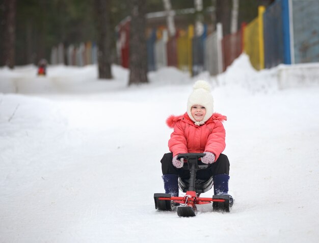 Kleiner Junge und Mädchen rutschen auf einem Schlitten vom Schneehügel herunter