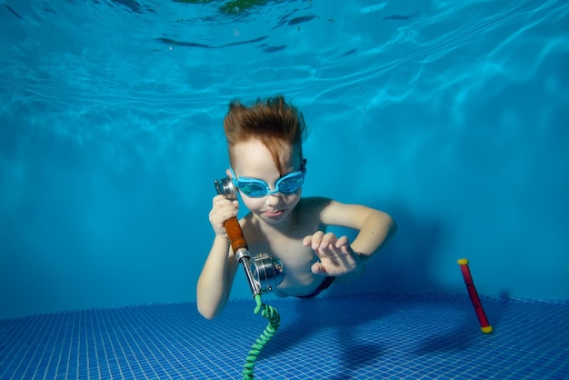 Kleiner Junge unter Wasser im Schwimmbad liegt unten und telefoniert