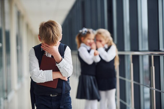 Kleiner Junge wird gemobbt Konzeption von Belästigung Schulkinder in Uniform zusammen im Korridor