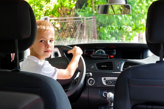 Kleiner Kinderjunge hinter dem Lenkrad eines Autos