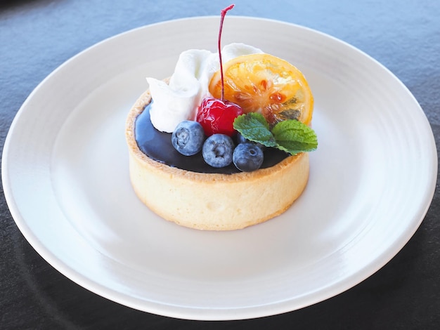 Kleiner Kuchen mit Obst und Schlagsahne auf weißem Teller