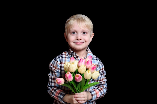 Kleiner lächelnder blonder Junge, der einen Strauß Tulpen hält. Porträt.