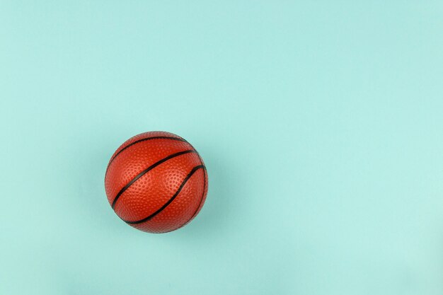 Kleiner orangefarbener Ball für Basketballsportspiel auf blauem Hintergrund.