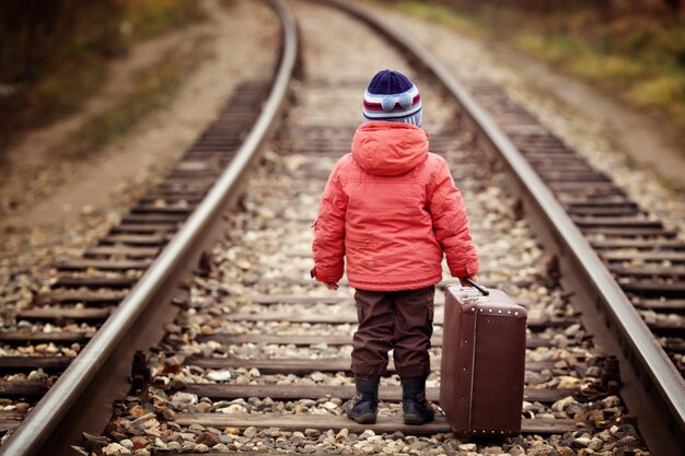 kleiner Reisender mit einem Koffer auf der Eisenbahn