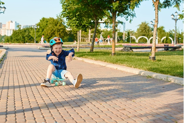 Kleiner rothaariger Junge fährt im Sommer Skateboard im Park