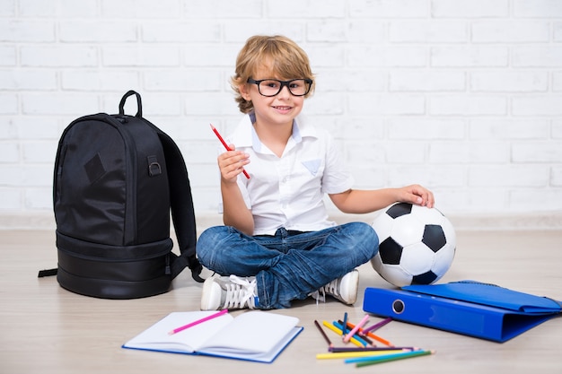 Kleiner Schuljunge mit Brille, der zu Hause Hausaufgaben macht