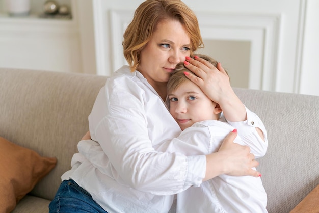 Kleiner sohn gratuliert mama zum muttertag zu hause glückliche fraumutter mit kaukasischem aussehen umarmt h...