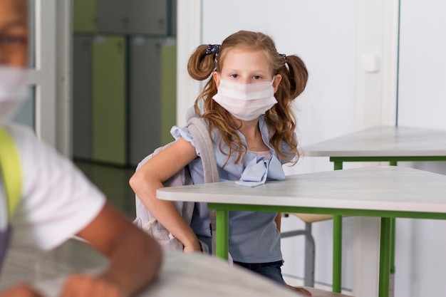 Kleiner Student, der eine medizinische Maske trägt