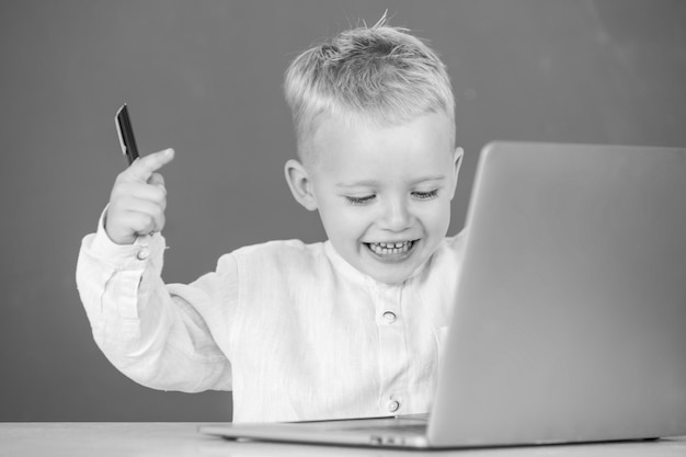 Kleiner Studentenjunge mit Laptop-Computer in der Schulklasse