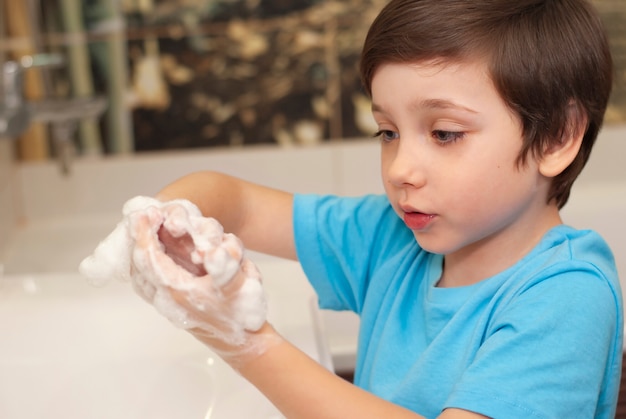 Kleiner süßer Junge, der Hände sorgfältig mit Seife wäscht, um gesund zu sein, um Infektionsgrippe zu verhindern