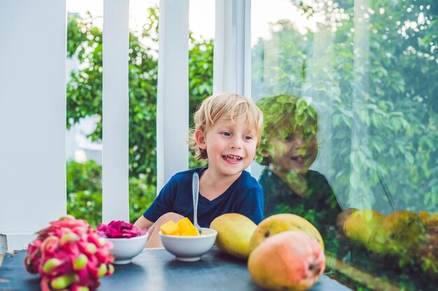 Kleiner süßer Junge, der Mango auf der Terrasse isst.