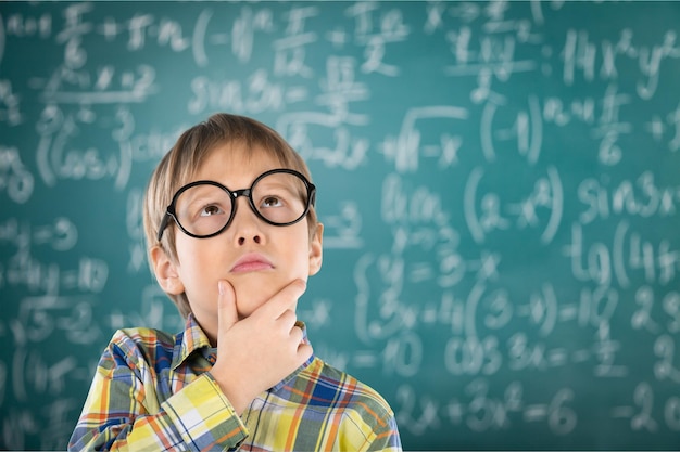 Kleiner süßer Junge mit Brille in der Nähe der grünen Tafel