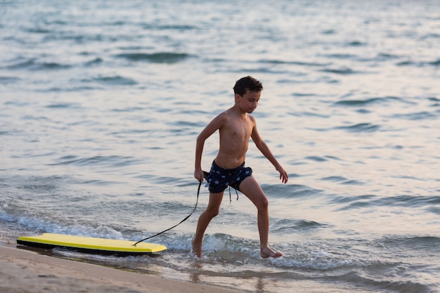 Kleiner Surfer laufen mit Bodyboard zum Meer zum Wellenreiten