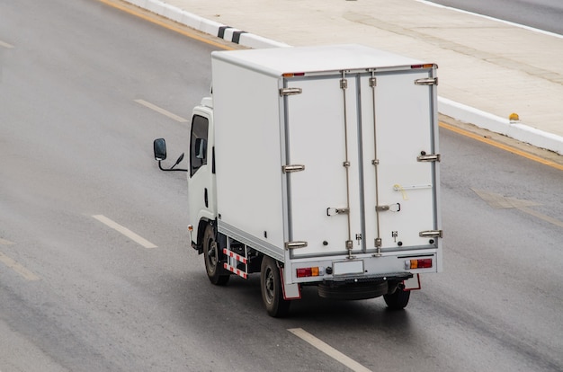 Kleiner weißer LKW, der auf der Straße läuft.