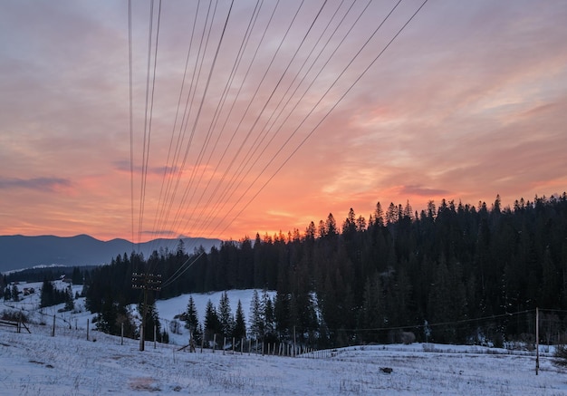 Kleines alpines Dorf und schneebedeckte Winterberge im ersten Sonnenaufgangssonnenlicht um Woronenko-Karpaten-Ukraine