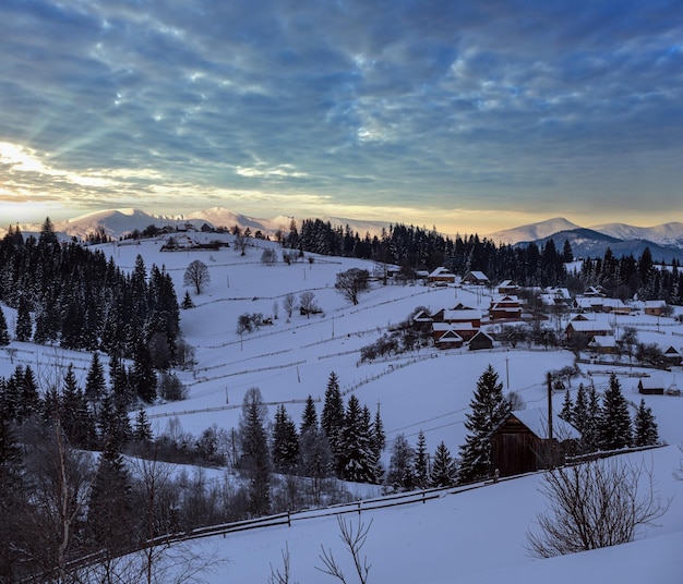 Kleines alpines Dorf und winterliche schneebedeckte Berge im ersten Sonnenaufgang um Voronenko Karpaten Ukraine