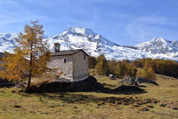 Kleines alpines Kapellengebäude auf einem Felsen mit schneebedecktem Gebirgshintergrund im europäischen Nationalpark