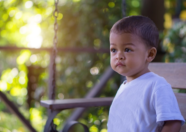 Kleines asiatisches Baby, das morgens Zeit mit Naturhintergrund morgens schaut