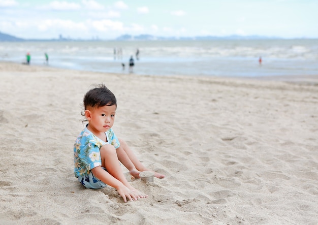 Kleines asiatisches Baby entspannen auf Sand am Strand