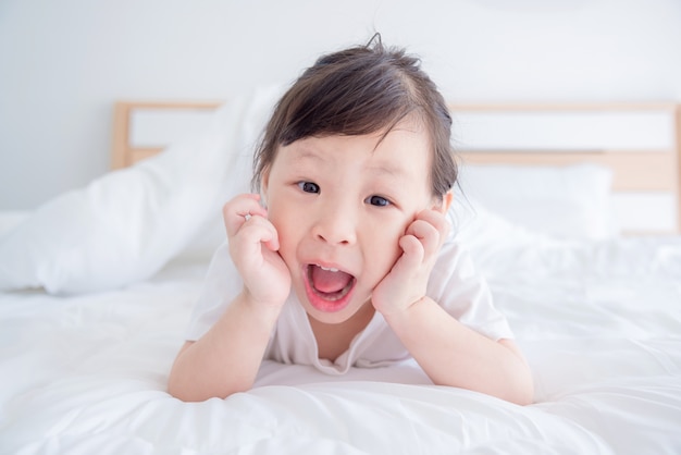 Kleines asiatisches Mädchen, das auf Bett liegt