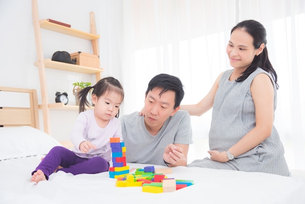 Kleines asiatisches Mädchen, das zu Hause Holzklötze mit ihrem Vater und Mutter spielt