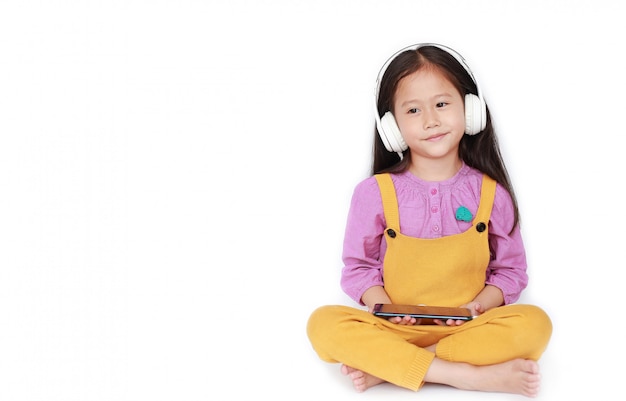 Kleines asiatisches Mädchen des Porträts genießt, Musik durch Kopfhörer zu hören