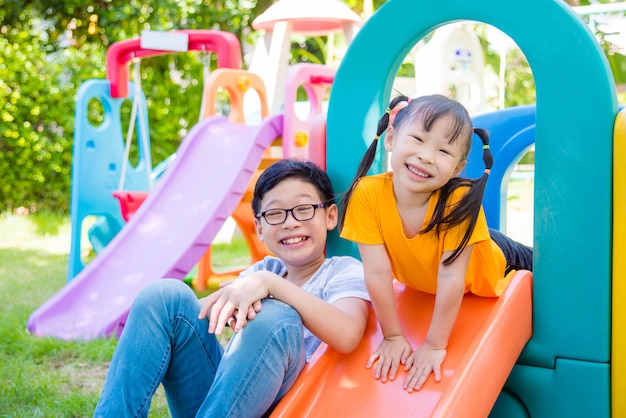 Kleines asiatisches Mädchen und ihr Bruder, die am Schulspielplatz spielen