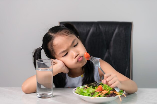 Kleines asiatisches süßes Mädchen weigert sich, gesundes Gemüse zu essenErnährungskonzept für gesunde Ernährung für KinderKinder essen kein Gemüse gern