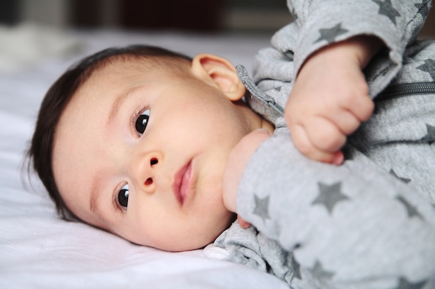 Kleines Baby, das auf das Bett im Reinraum kriecht. Auf seinem Gesichtsinteresse und Wundern. Europäisch. Baby überrascht.