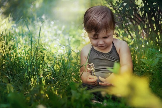 Kleines Baby, das im Gras sitzt und die Natur untersucht