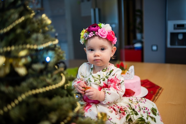 Kleines Baby in der Nähe von Weihnachtsbaum vor der Neujahrsparty