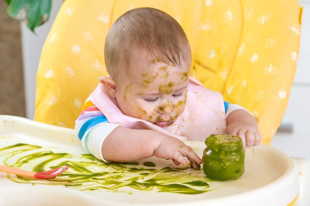 Kleines Baby isst selbst Brokkolipüree. Selektiver Fokus. Menschen.